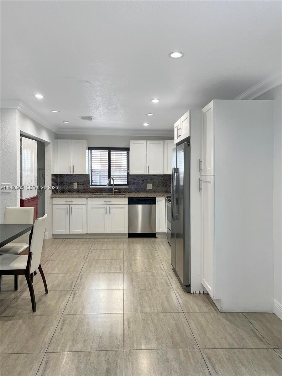 A kitchen features white cabinets, stainless steel appliances, and light-colored tile flooring — 221 W 31st St, Hialeah FL 33012, HIALEAH, FL
