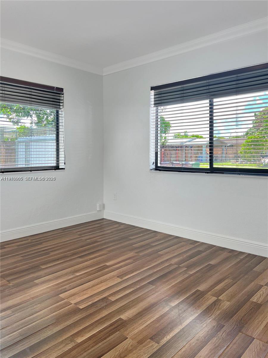 An empty room features light-colored walls, wood-look flooring, and two windows with horizontal blinds — 221 W 31st St, Hialeah FL 33012, HIALEAH, FL