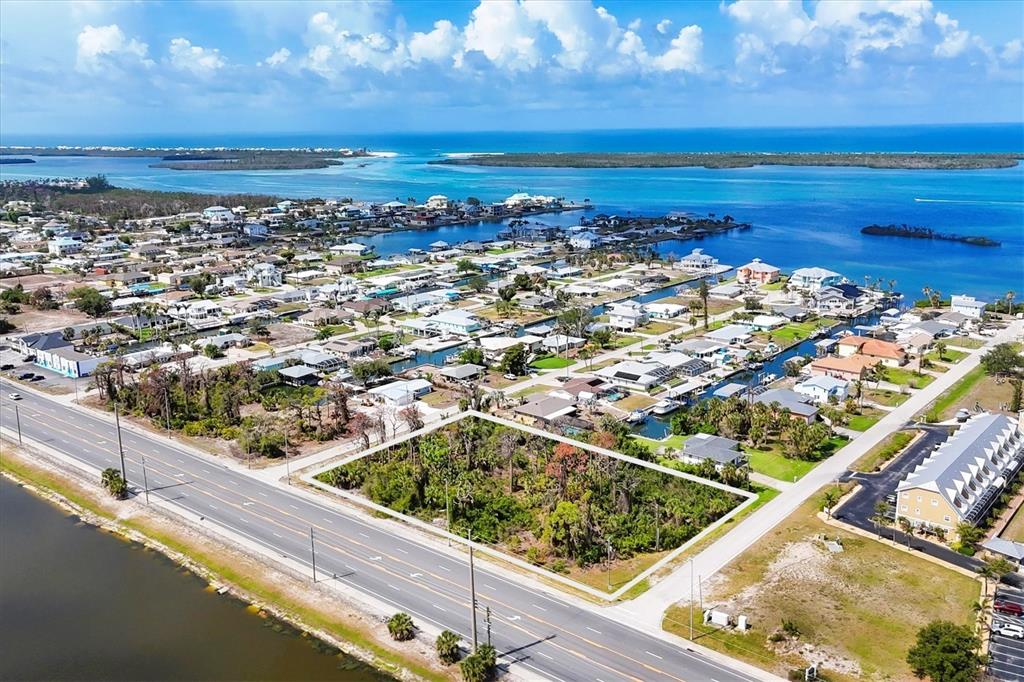 An aerial view shows a vacant, rectangular lot bordered by a road and water — 2440 PLACIDA ROAD, ENGLEWOOD, FL
