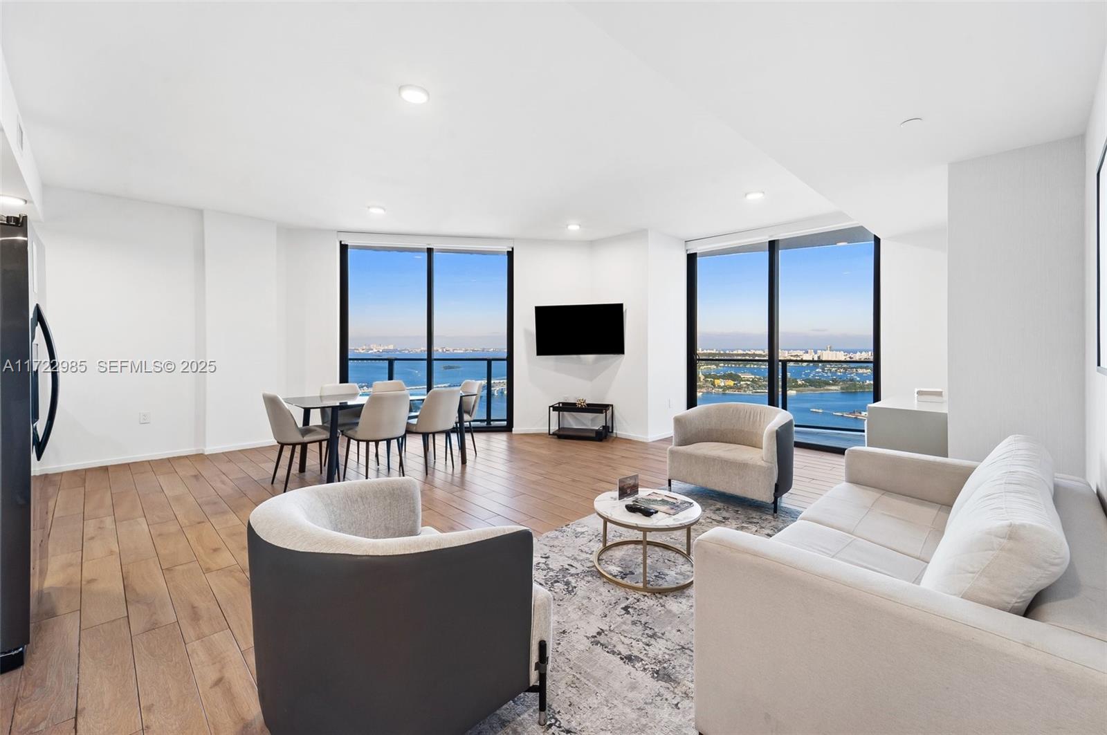 A modern living and dining area features floor-to-ceiling windows with expansive waterfront city views — 398 NE 5th St # 3209, Miami FL 33132, MIAMI, FL