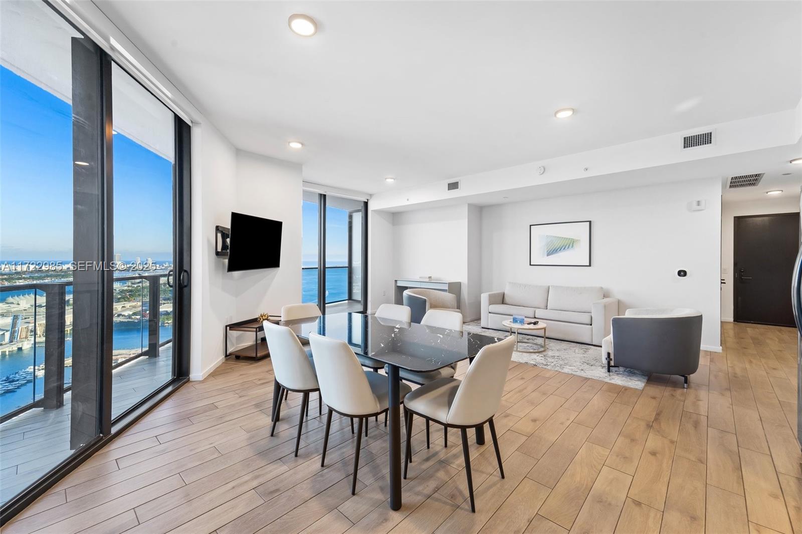 A modern open-concept living and dining area features floor-to-ceiling windows with ocean views — 398 NE 5th St # 3209, Miami FL 33132, MIAMI, FL