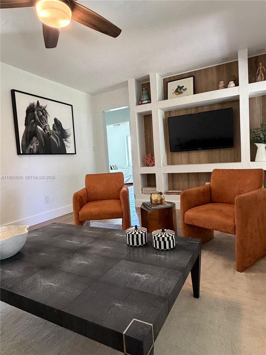A living room features two orange armchairs, a black coffee table, and built-in shelving — 11201 NE 10th Ave # 11201, Biscayne Park FL 33161, BISCAYNE PARK, FL