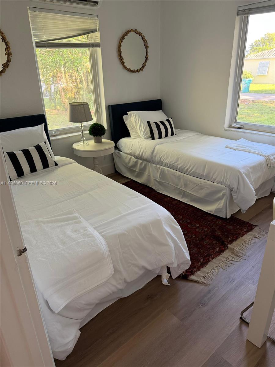 A bedroom features two twin beds with white bedding and black-and-white striped accent pillows — 11201 NE 10th Ave # 11201, Biscayne Park FL 33161, BISCAYNE PARK, FL