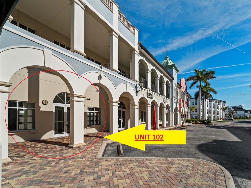 The exterior of a commercial building features a covered walkway with arched columns and brick pavers — 3976 DESTINATION DRIVE UNIT 102, OSPREY, FL