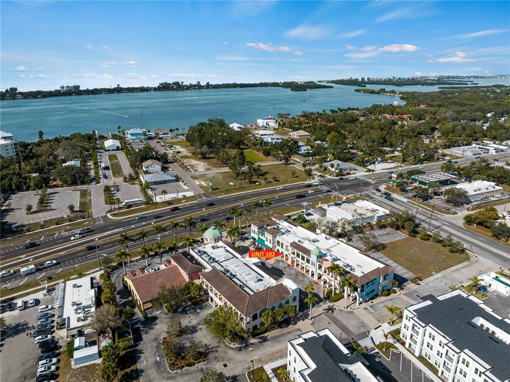 An aerial view shows a commercial building complex near a road and a large bay — 3976 DESTINATION DRIVE UNIT 102, OSPREY, FL