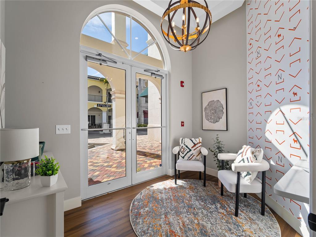 A bright entryway features double glass doors, two armchairs, a round rug, and patterned wallpaper — 3976 DESTINATION DRIVE UNIT 102, OSPREY, FL