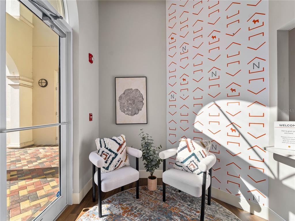 A small entryway features two white chairs, a patterned rug, and a geometric wall design — 3976 DESTINATION DRIVE UNIT 102, OSPREY, FL
