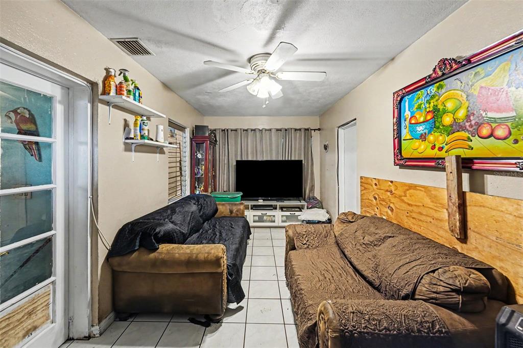 A living room features two brown sofas, a television on a stand, and tile flooring — 110 N JUPITER AVENUE, CLEARWATER, FL