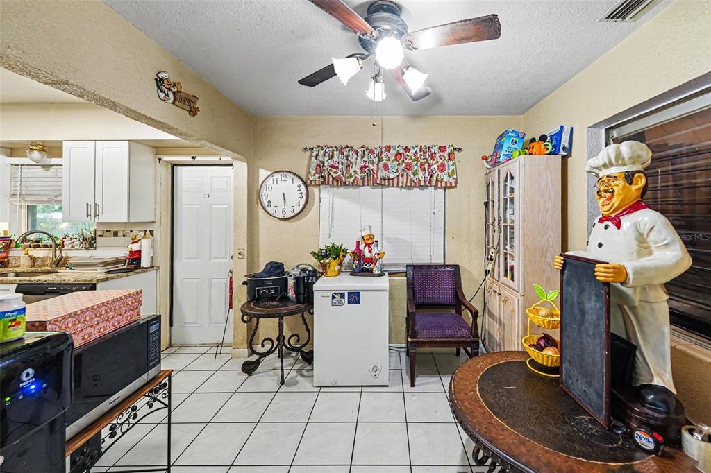 A kitchen and dining area with white cabinets, tile flooring, and a chef statue — 110 N JUPITER AVENUE, CLEARWATER, FL