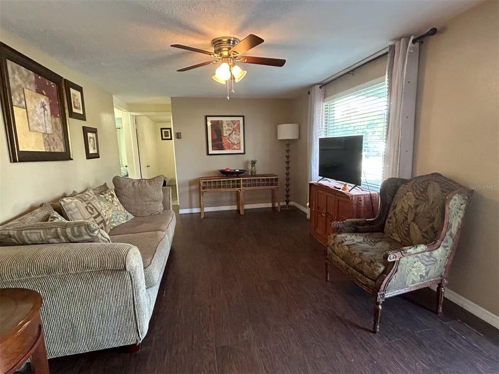 A living room features dark wood flooring, a ceiling fan, a sofa, and an armchair — 2048 MELODY DRIVE, HOLIDAY, FL