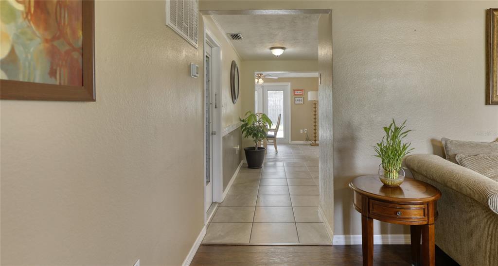 A tiled hallway leads from a living area toward a bright room with glass doors — 2048 MELODY DRIVE, HOLIDAY, FL