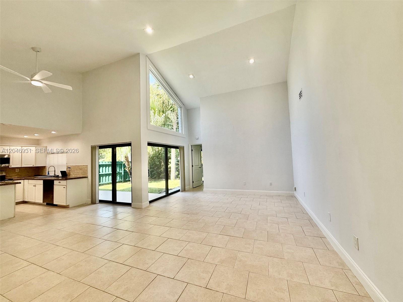 A spacious living area with high ceilings, tile floors, and large windows overlooking a yard — 20910 Estada Ln, Boca Raton FL 33433, BOCA RATON, FL