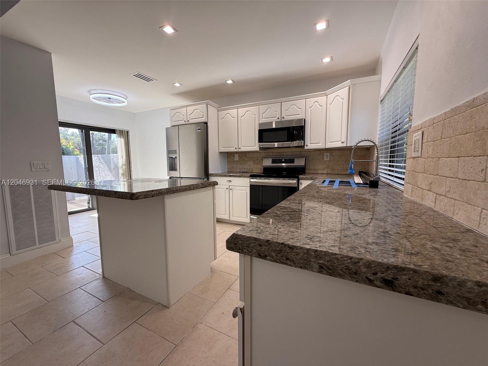 A kitchen features white cabinets, granite countertops, stainless steel appliances, and tile flooring — 20910 Estada Ln, Boca Raton FL 33433, BOCA RATON, FL