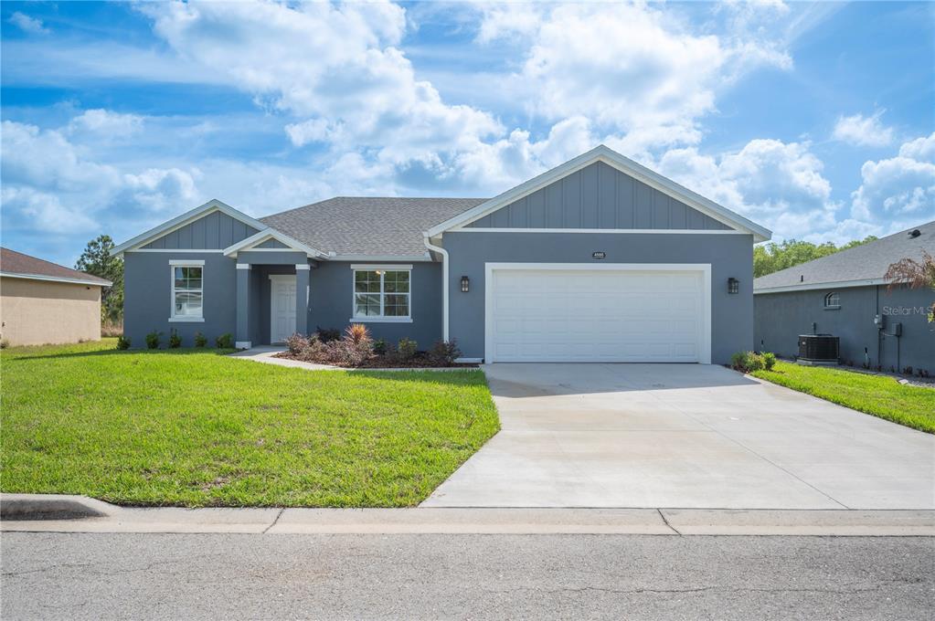 A single-story house with gray siding, a white garage door, and a front lawn — 4550 FAIRWAY OAKS DRIVE, MULBERRY, FL