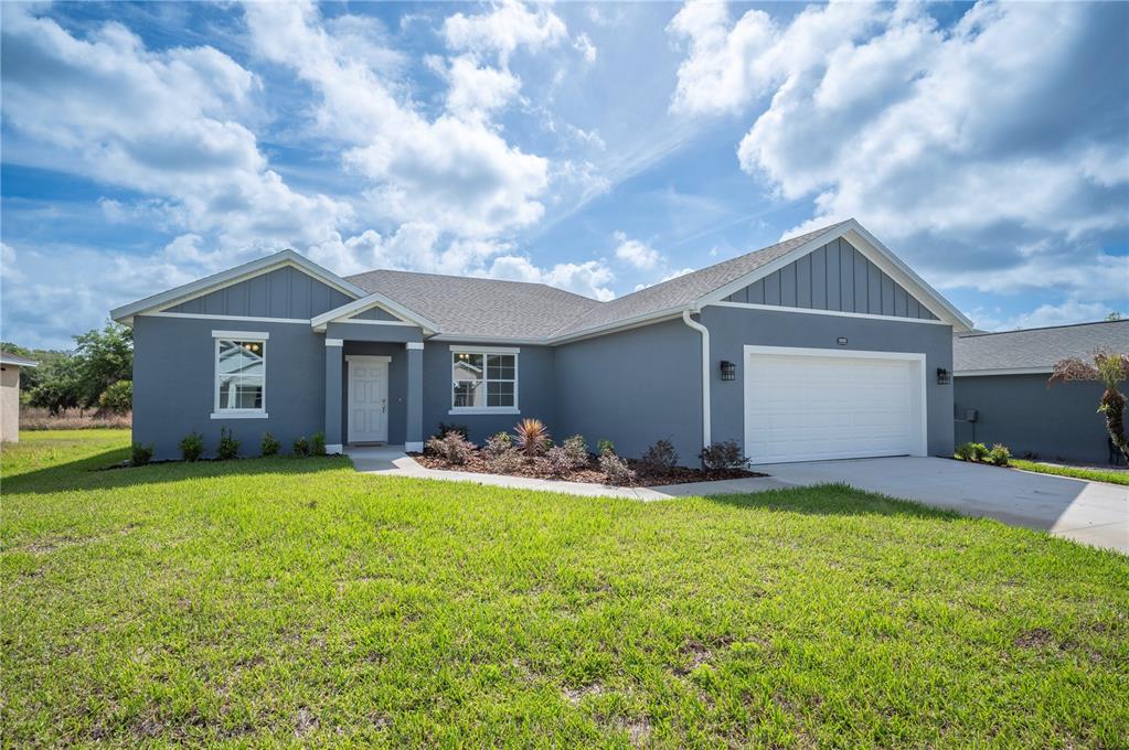 A single-story gray house with a white garage door and a front entryway — 4550 FAIRWAY OAKS DRIVE, MULBERRY, FL