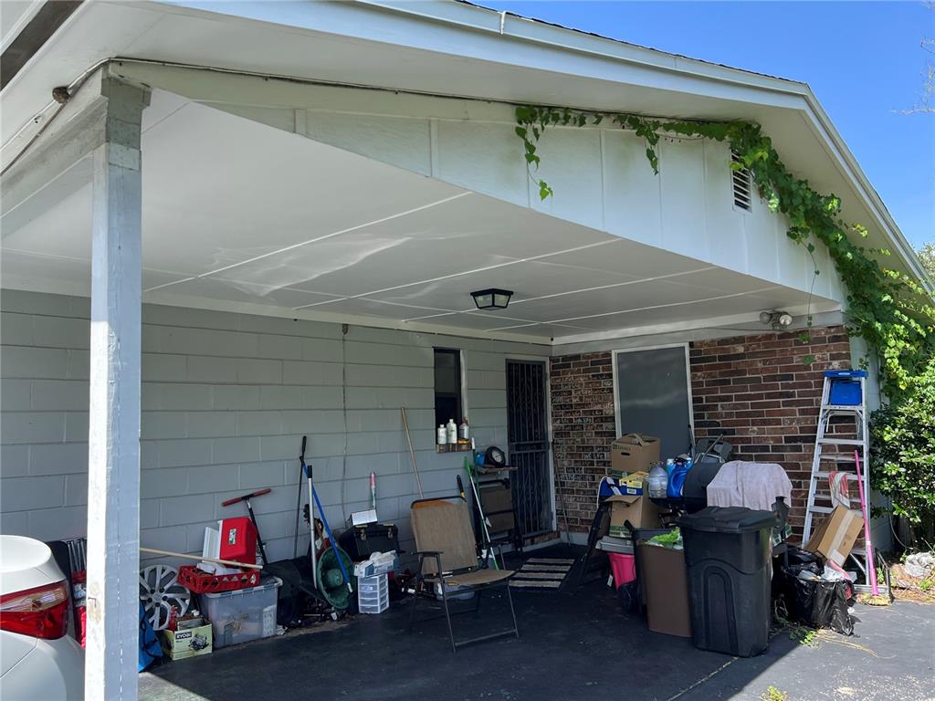 A covered carport with a concrete floor, brick and siding walls, and various stored items — 5145 SAGINAW AVENUE, JACKSONVILLE, FL