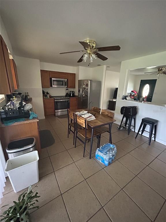 This kitchen features wooden cabinets, stainless steel appliances, a dining table, and tile flooring — 3544 COLLEEN DRIVE, LAKELAND, FL