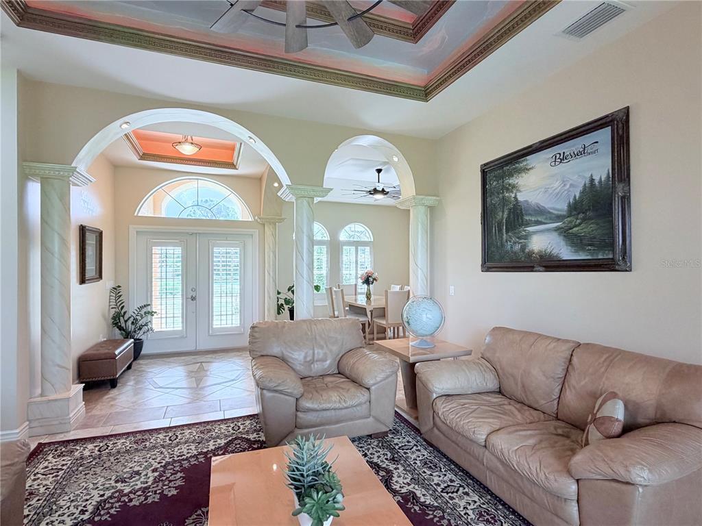 A living room features arched entryways, decorative columns, a tray ceiling, and tan leather furniture — 324 SANTURCE AVENUE, NORTH PORT, FL