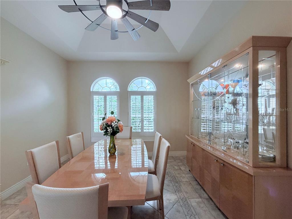 A dining room features a glossy table, six chairs, a large display cabinet, and arched windows — 324 SANTURCE AVENUE, NORTH PORT, FL