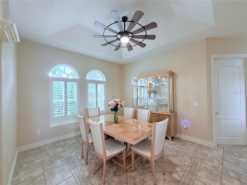 A dining room features a tray ceiling, tile flooring, a glass-front cabinet, and arched windows — 324 SANTURCE AVENUE, NORTH PORT, FL