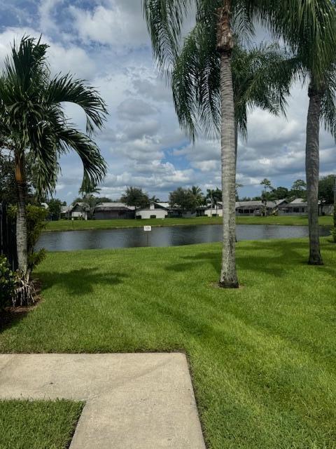 A grassy lawn leads to a pond with palm trees and houses in the background — 1171 Summit Trail Circle # C, West Palm Beach FL 33415, WEST PALM BEACH, FL