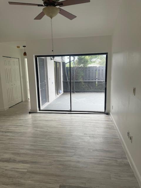 An empty living room with light wood-look flooring, a ceiling fan, and sliding glass patio doors — 1171 Summit Trail Circle # C, West Palm Beach FL 33415, WEST PALM BEACH, FL