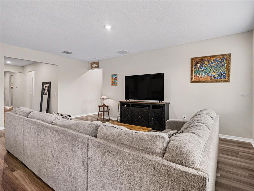 A living room features a large gray sectional sofa, a television on a dark console — 293 DAYLILY BOULEVARD, NOKOMIS, FL