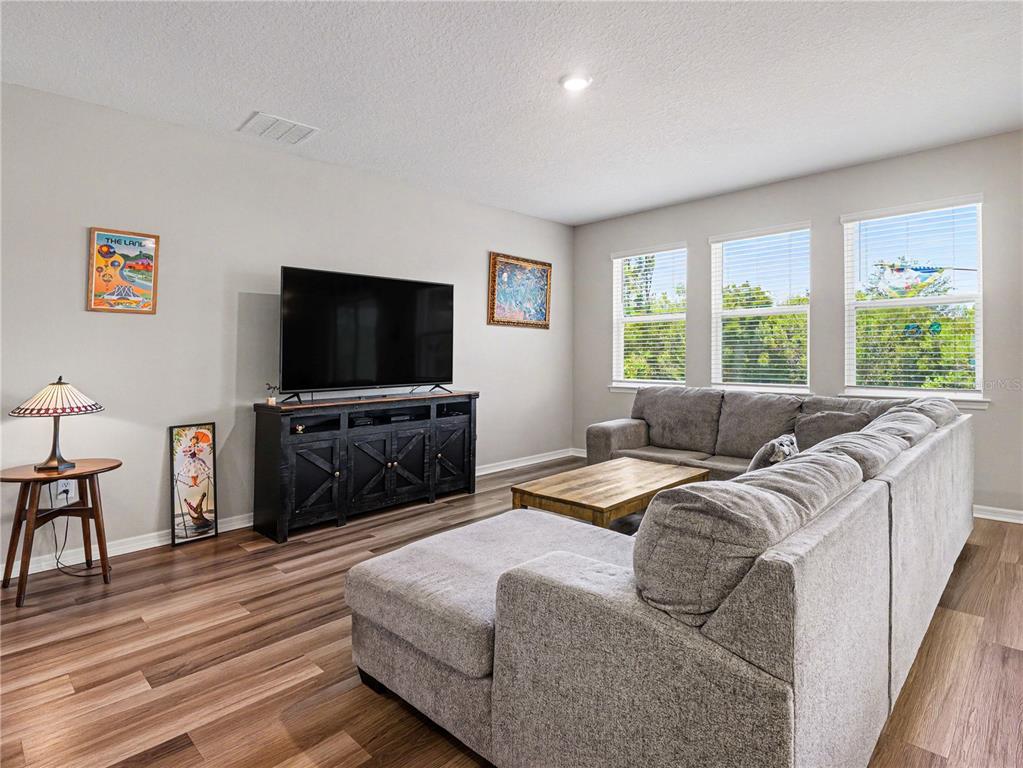 A living room features gray sectional seating, a television on a dark console, and wood-look flooring — 293 DAYLILY BOULEVARD, NOKOMIS, FL