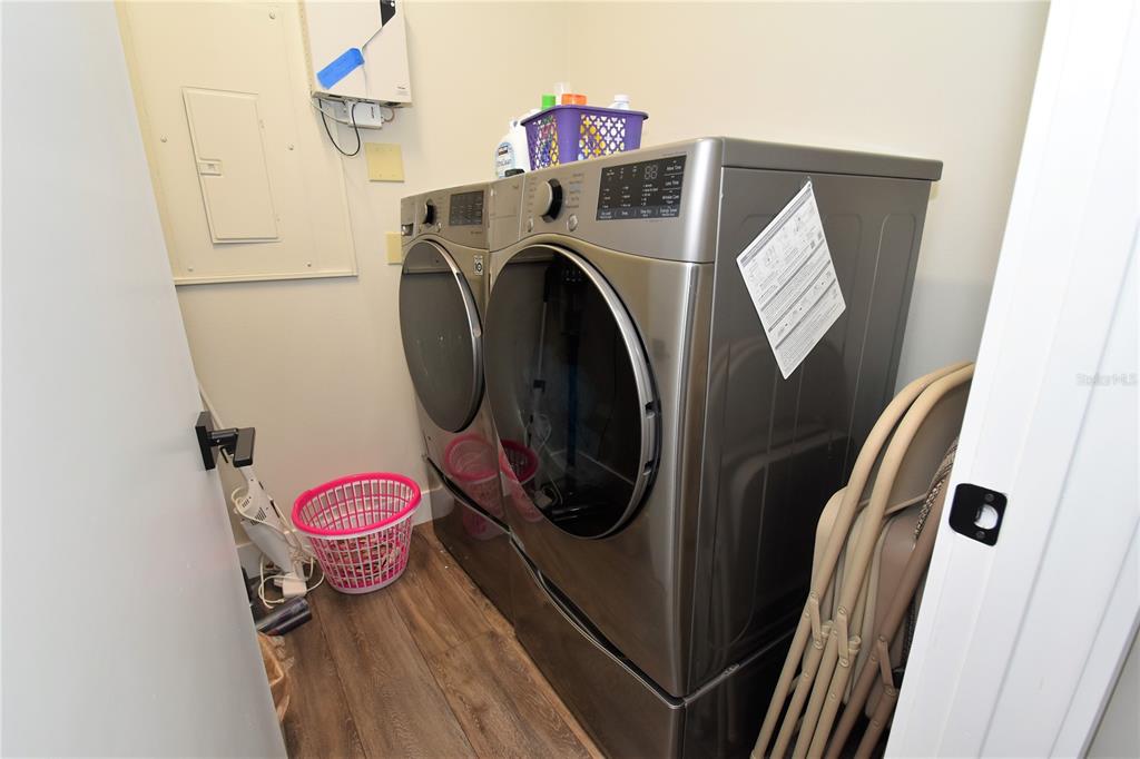 A laundry closet contains a gray washer and dryer set, a pink basket, and folding chairs — 1631 STARLING DRIVE UNIT 204, SARASOTA, FL