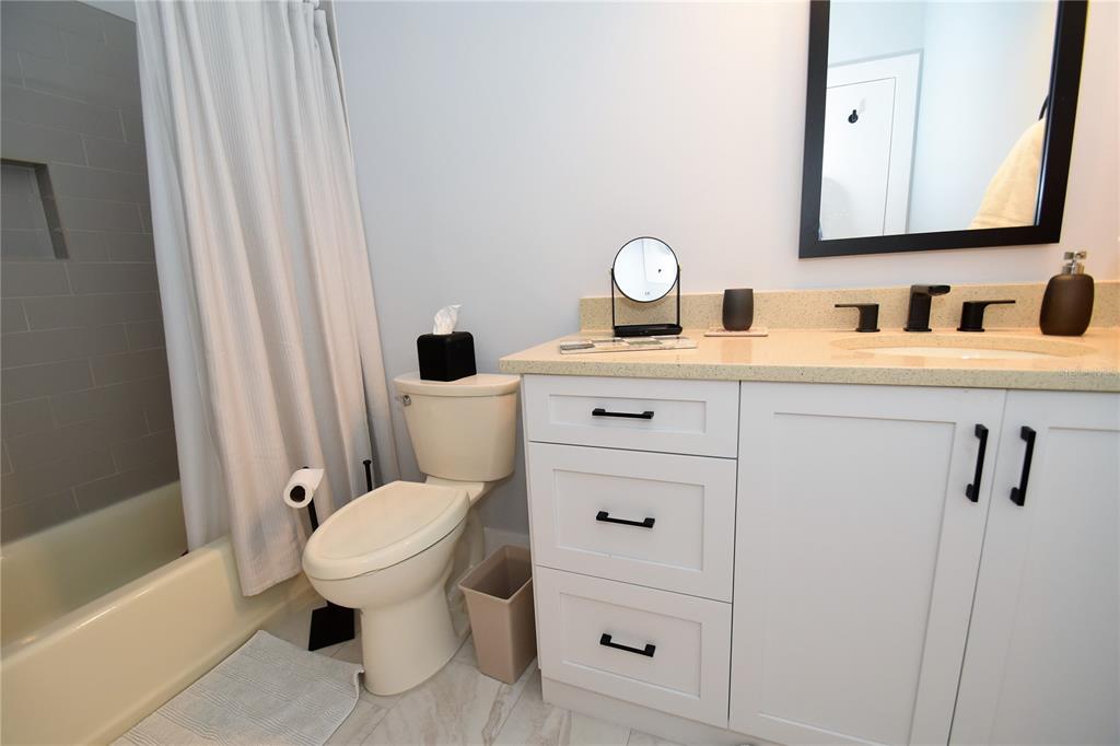 A bathroom features a white vanity with black hardware, a toilet, and a shower-tub combination — 1631 STARLING DRIVE UNIT 204, SARASOTA, FL