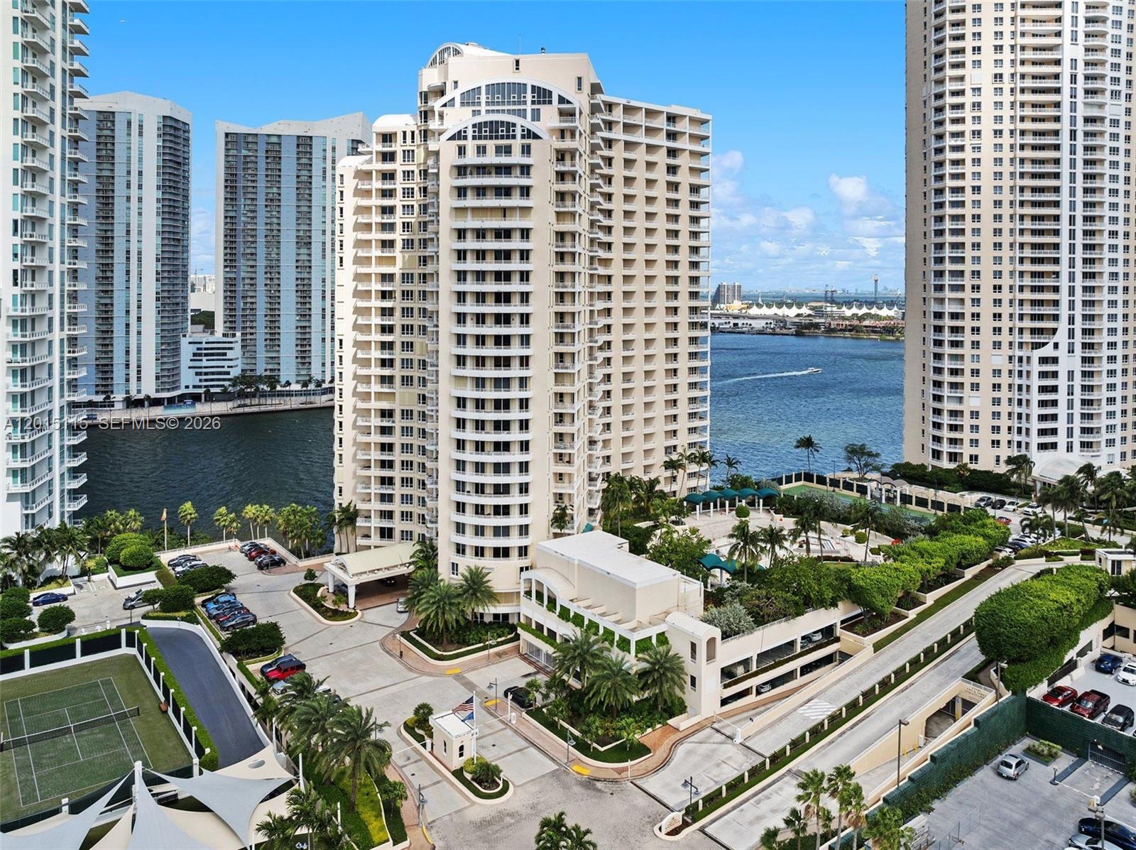 An aerial view shows a tall residential building with a gated entrance and tennis courts — 888 Brickell Key Dr # 609, Miami FL 33131, MIAMI, FL