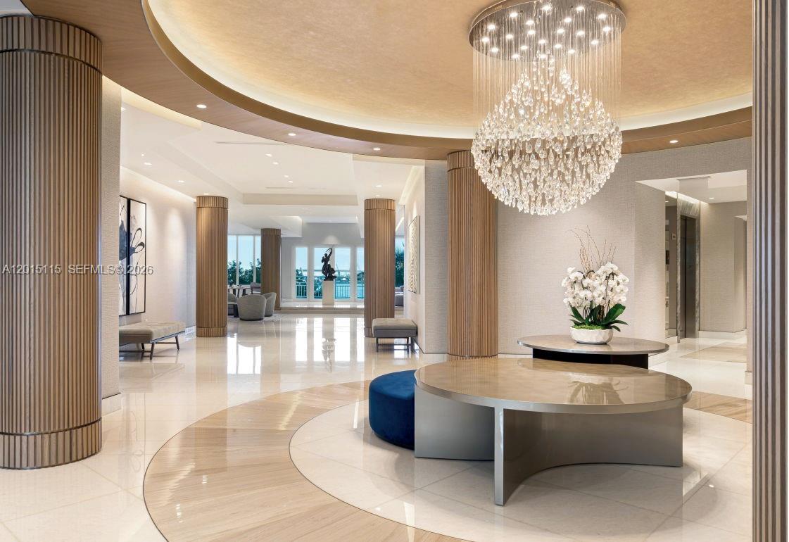 A luxurious lobby features a large crystal chandelier, polished tile floors, and fluted wooden columns — 888 Brickell Key Dr # 609, Miami FL 33131, MIAMI, FL