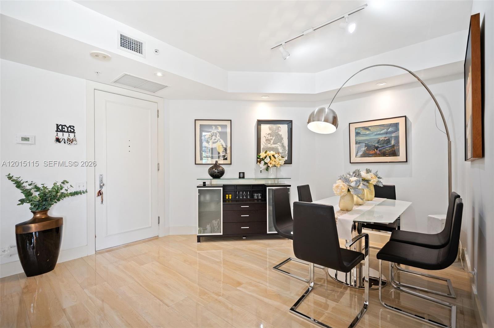 A dining room features a glass table, black chairs, a sideboard, and an arched lamp — 888 Brickell Key Dr # 609, Miami FL 33131, MIAMI, FL