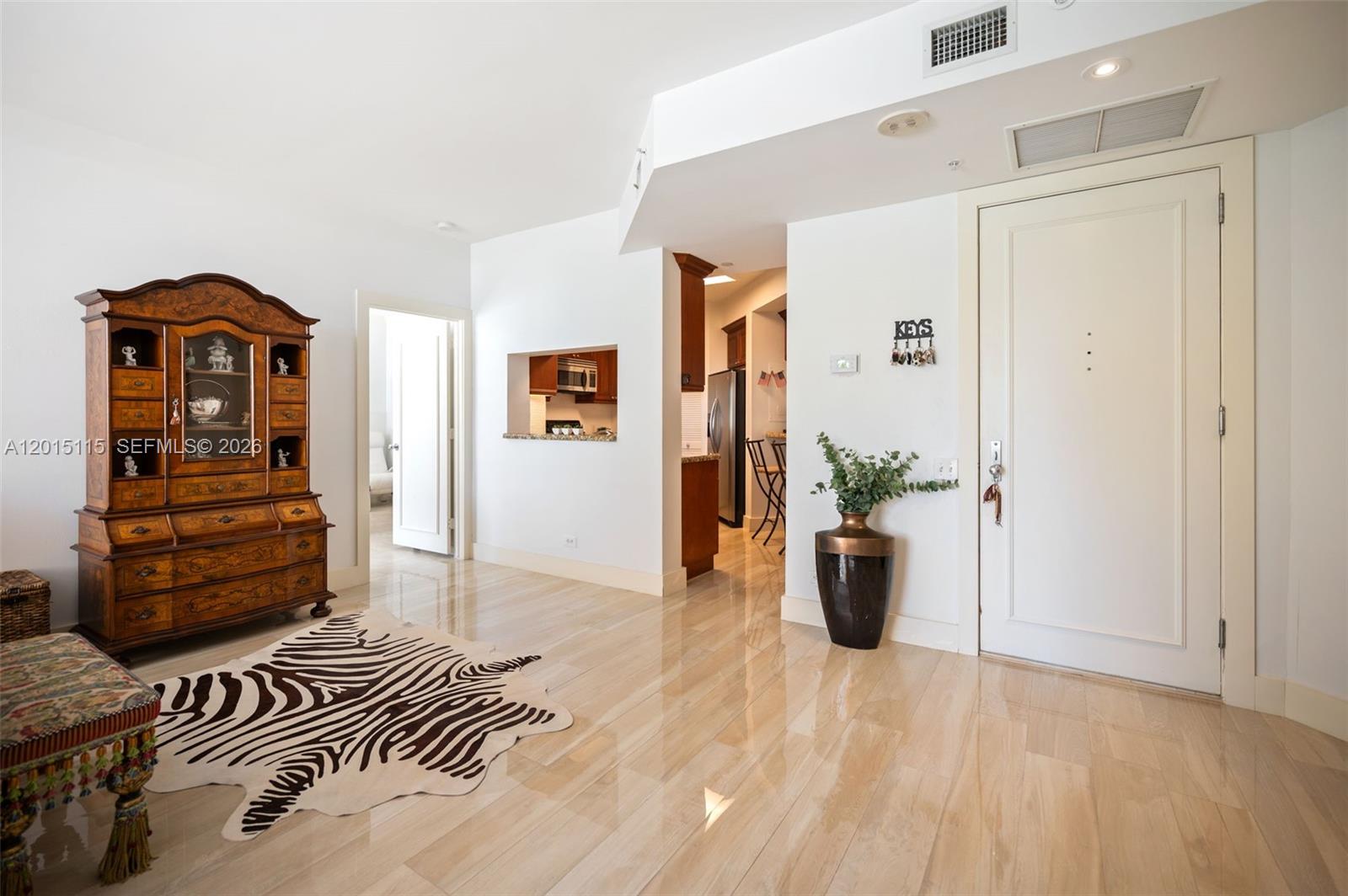 An entryway features light wood-look tile flooring, a zebra-print rug, and a large wooden hutch — 888 Brickell Key Dr # 609, Miami FL 33131, MIAMI, FL