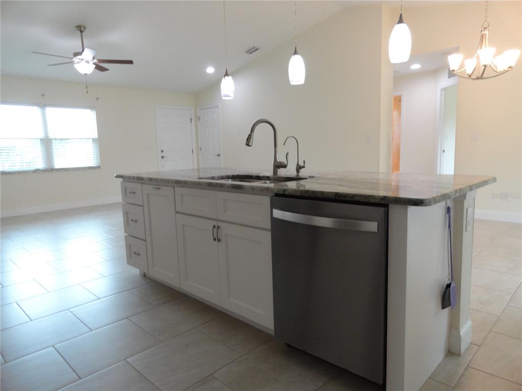 A kitchen island with white cabinets, a stainless steel dishwasher, and a granite countertop — 2580 VOGLER LANE, NORTH PORT, FL