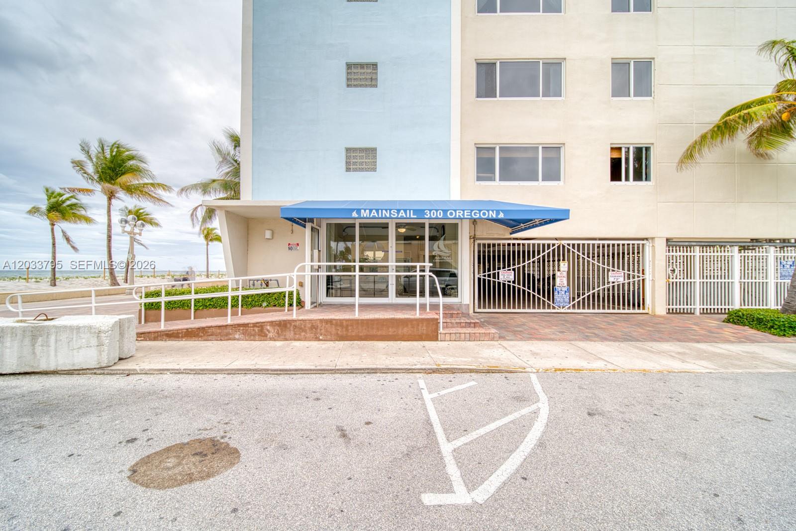 The exterior of a multi-story building features a blue awning over the main entrance — 300 Oregon St # 507, Hollywood FL 33019, HOLLYWOOD, FL