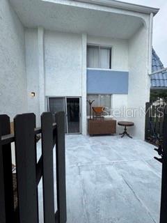A fenced concrete patio leads to the sliding glass door entrance of a two-story home — 1871 PINE CONE CIRCLE UNIT 1, CLEARWATER, FL