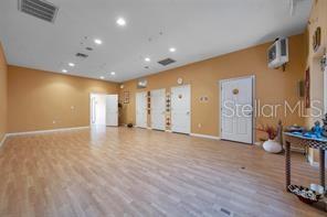 A spacious room with light wood-look flooring, tan walls, and multiple white doors — 2625 KEYSTONE ROAD UNIT 2, TARPON SPRINGS, FL