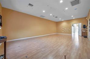 A spacious, empty room features light wood-look flooring, tan walls, and recessed ceiling lighting — 2625 KEYSTONE ROAD UNIT 2, TARPON SPRINGS, FL