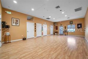 A spacious room features light wood-look flooring, tan walls, and multiple white doors — 2625 KEYSTONE ROAD UNIT 2, TARPON SPRINGS, FL