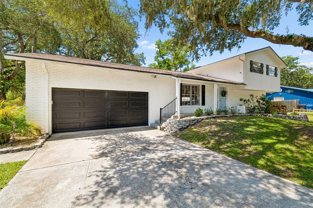 A white brick house with a black garage door and a concrete driveway — 114 WINDY CIRCLE, BRANDON, FL