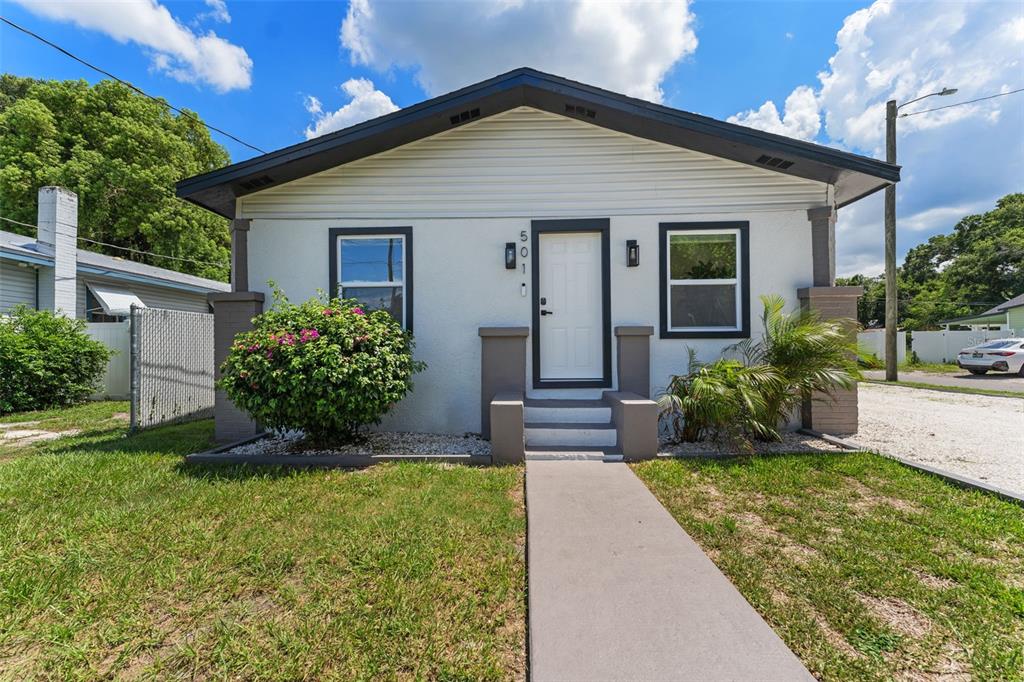 A single-story house with a white exterior, dark trim, and a concrete walkway leading to stairs — 501 E CLUSTER AVENUE, TAMPA, FL