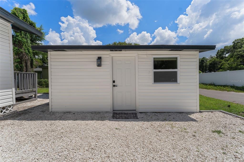 A white, single-story detached structure with a door, window, and gravel ground — 501 E CLUSTER AVENUE, TAMPA, FL