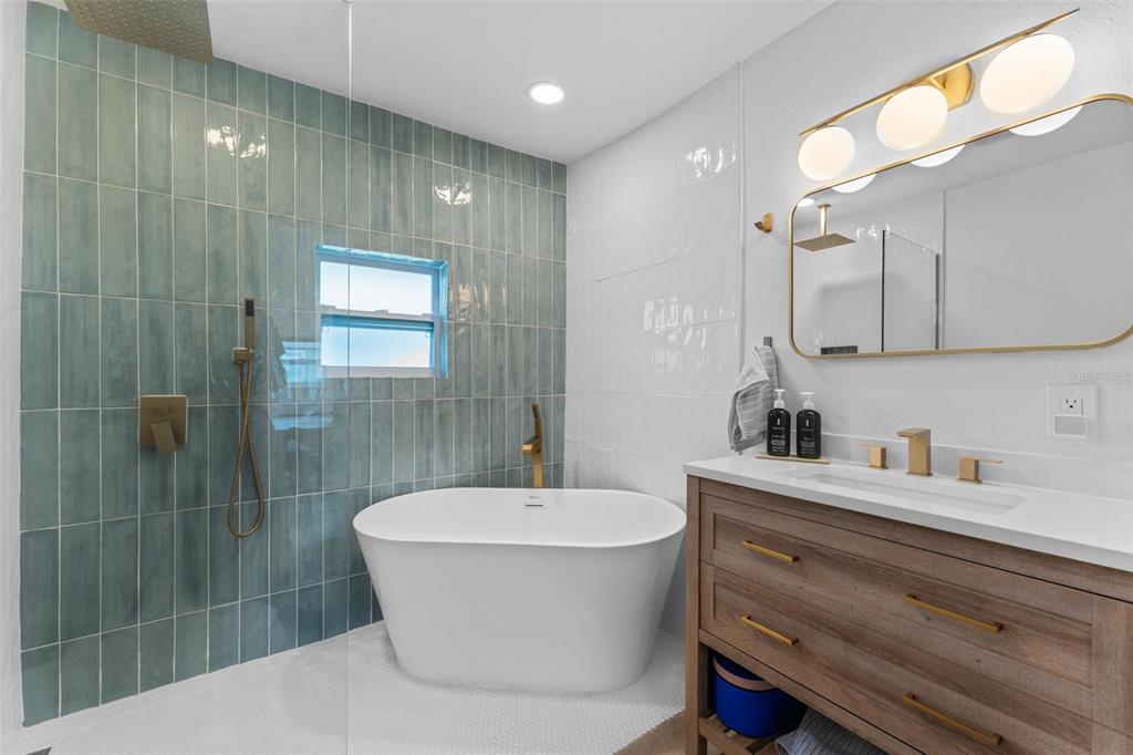 A bathroom features a freestanding tub, a glass-enclosed shower, and a wood vanity with gold fixtures — 501 E CLUSTER AVENUE, TAMPA, FL