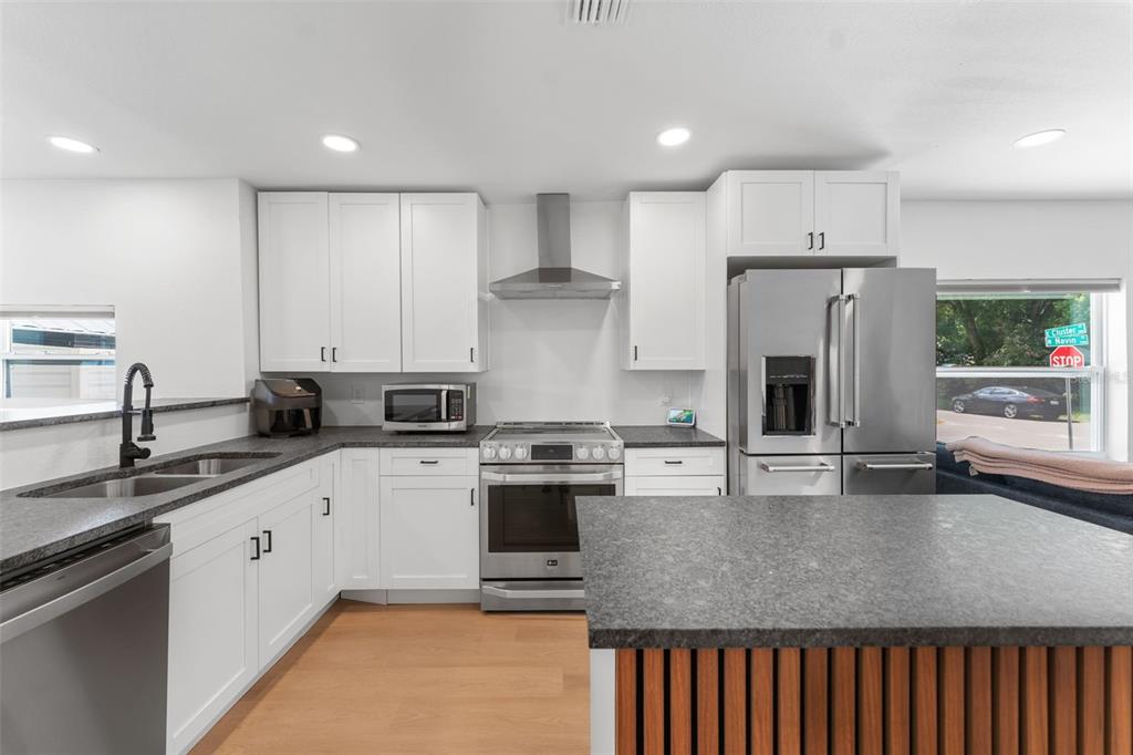 A modern kitchen features white cabinets, stainless steel appliances, and a dark stone countertop island — 501 E CLUSTER AVENUE, TAMPA, FL