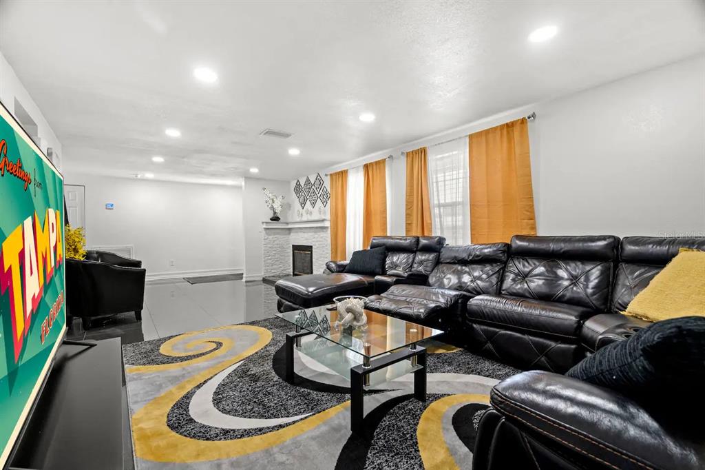 A living room features a black leather sectional, a glass coffee table, and a fireplace — 7005 FOUNTAIN AVENUE, TAMPA, FL