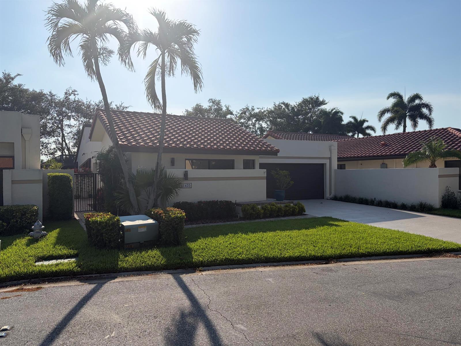 A single-story house with a tile roof, palm trees, and a driveway under a sunny sky — 21435 Campo Allegro Drive, Boca Raton FL 33433, BOCA RATON, FL