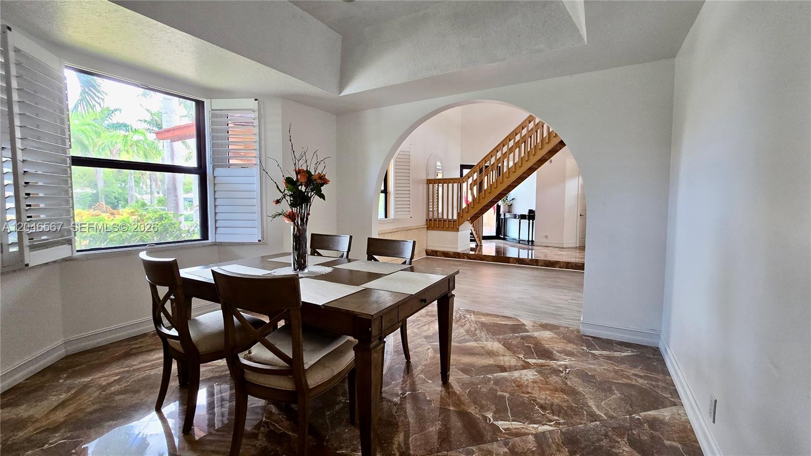 A dining room with a marble floor features an arched entryway leading to a staircase — 741 Tyler St # 0, Hollywood FL 33019, HOLLYWOOD, FL