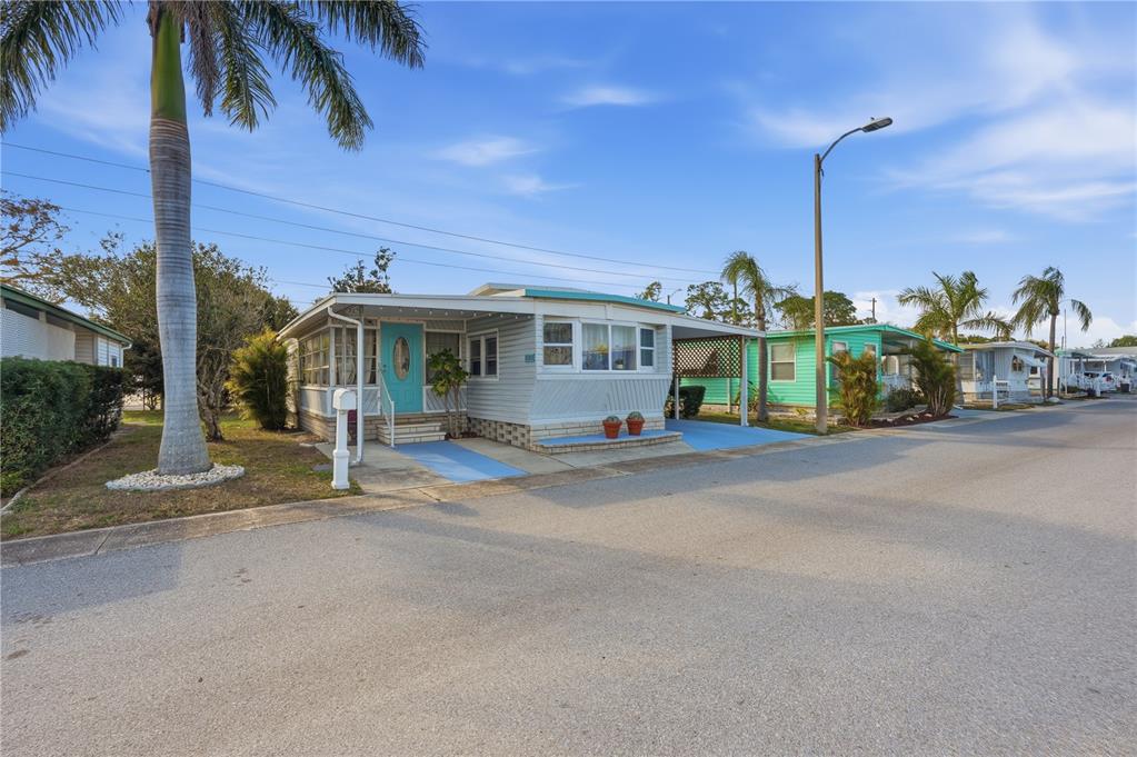 A light-colored mobile home with a turquoise door sits on a paved street — 82008 A STREET N UNIT 8, PINELLAS PARK, FL