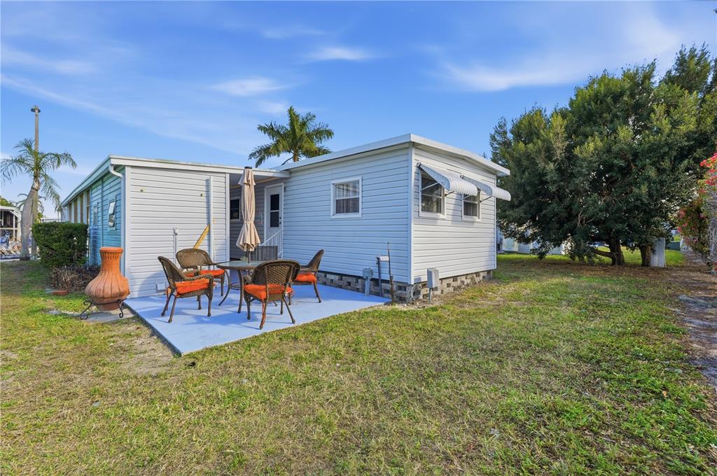 A light blue mobile home features a small patio with outdoor furniture and a lawn — 82008 A STREET N UNIT 8, PINELLAS PARK, FL